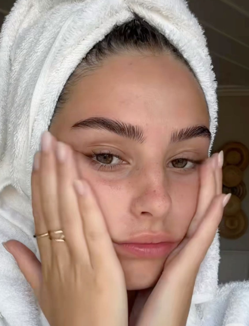 머리에 수건을 두르고 얼굴에 손을 올리고 있는 여자