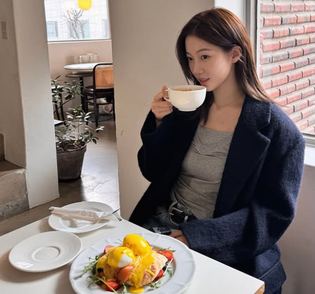 브런치 카페에서 여유를 즐기는 카즈하의 내추럴한 헤어 스타일과 슬리브리스 탑 코디