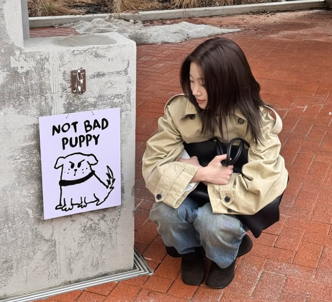 숏트렌치로 완성한 카즈하가 귀여운 포스터 옆에 쪼그려앉은 감성샷